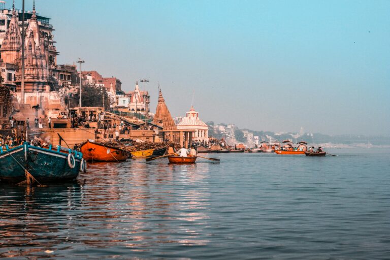 A colorful scene of Varanasi ghats and boats on the Ganges River, showcasing the city's rich culture.