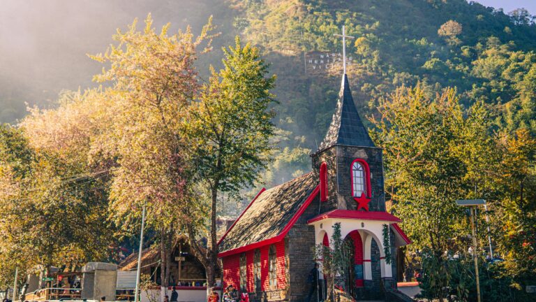 Charming church in Nagaland heritage village amidst autumn foliage and sunlight.