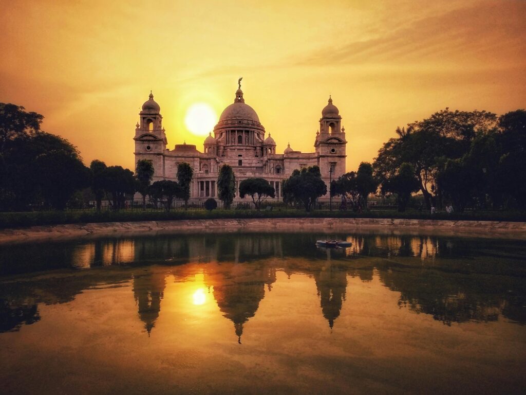 Captivating view of Victoria Memorial with sunset reflection on tranquil water in Kolkata, India.